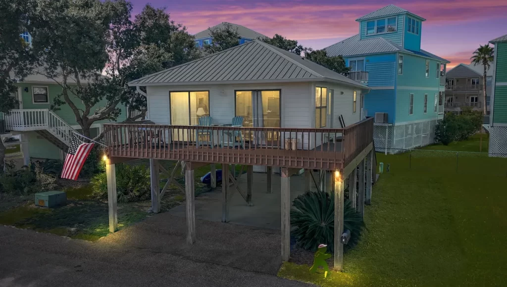 beach house image with sunset in background and american flag flying from deck
